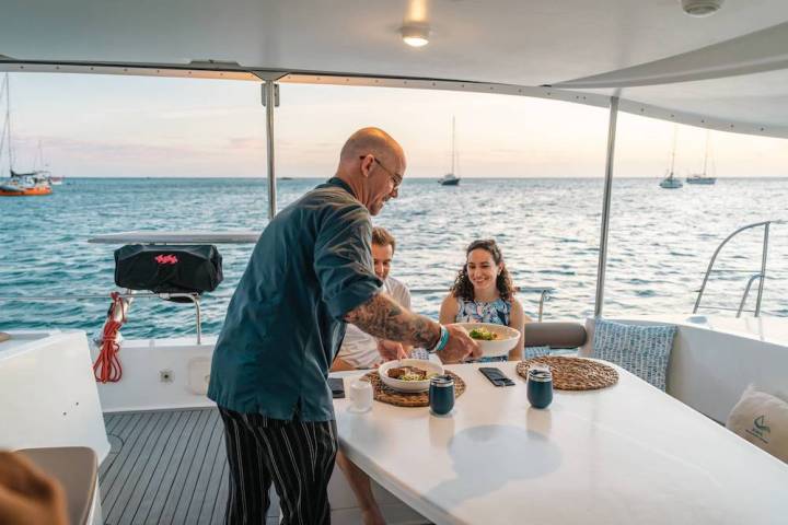 Crew serving lunch to guests in the shaded cockpit of AWA's catamaran in Aruba